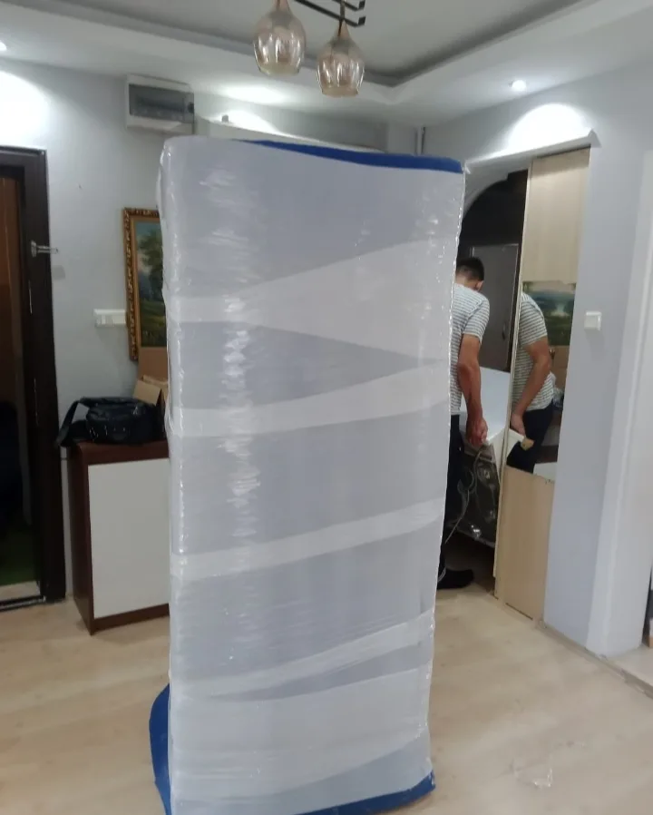 Kayacu Kardeşler ekibi streçle paketlenmiş dolabın yanında çalışırken