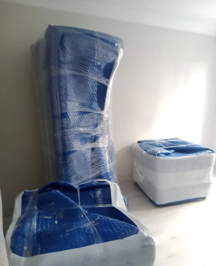 Boş odada mavi naylonla paketlenmiş dolap ve kutular